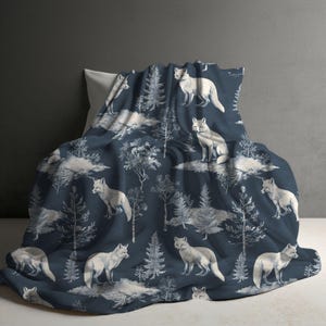May include: A dark navy blue blanket featuring a repeating pattern of white foxes and evergreen trees. The design displays foxes in various standing and sitting positions interspersed with detailed illustrations of pine trees and forest foliage.