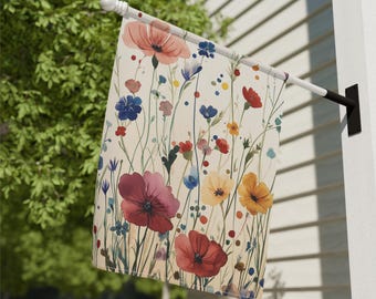 Puede incluir: Bandera de jardín con diseño floral de acuarela. Muestra flores rojas, rosas, azules y amarillas con tallos y hojas verdes sobre un fondo crema. La bandera está montada en un mástil blanco, ideal para exteriores.