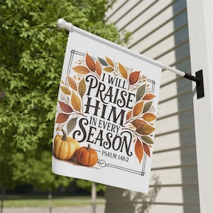May include: A white outdoor flag with the text "I WILL PRAISE HIM IN EVERY SEASON" and Psalm 146:2. The flag features a border of autumn leaves and two pumpkins. The flag is mounted on a white pole.