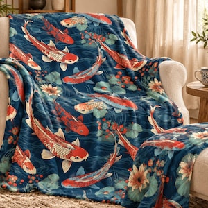 May include: A soft plush throw blanket featuring a repeating pattern of orange, white, and black koi fish swimming through dark blue water. The design includes scattered green lily pads and light-colored lotus flowers across the entire surface.