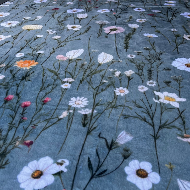 May include: A blue fabric with a white floral pattern. The fabric features a variety of white flowers, including daisies and other delicate blooms.
