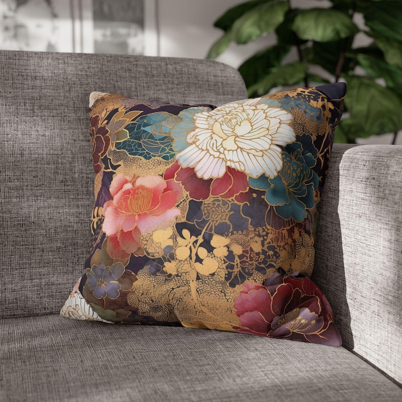 Puede incluir: Una almohada decorativa con un patr&oacute;n floral. La almohada presenta un fondo oscuro con flores grandes y coloridas en tonos de rosa, rojo, blanco y dorado. Las flores est&aacute;n rodeadas de intrincados dise&ntilde;os de pan de oro.
