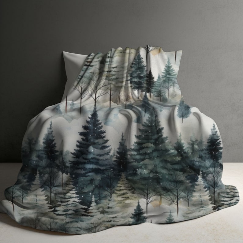 May include: A soft, white throw blanket with a watercolour print of a winter forest scene. The blanket features a variety of trees in shades of blue and green, with a subtle snowfall effect.