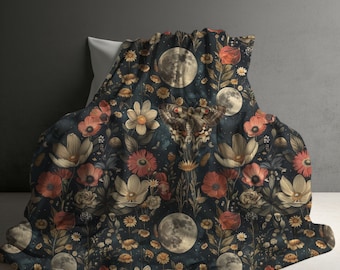 May include: A dark navy blue blanket featuring a repeating pattern of cream and red flowers, detailed moths with red accents, and full moons. The fabric displays a dense botanical and celestial print with various floral shapes and lunar phases.
