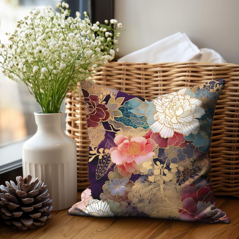 Puede incluir: Una almohada decorativa con un patr&oacute;n floral que presenta grandes flores rosas, blancas y rojas sobre un fondo morado oscuro con detalles dorados.