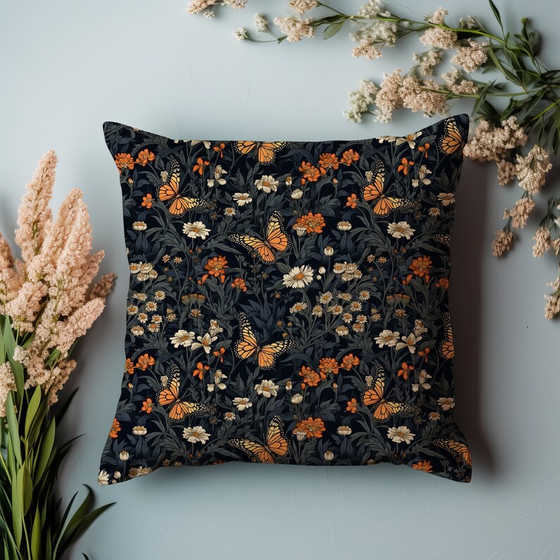 May include: A black throw pillow with a floral pattern featuring orange butterflies and white flowers on a dark background.