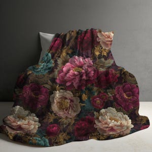 May include: A soft blanket featuring a dark, moody floral pattern with large, blooming peonies in shades of deep burgundy, soft pink, and muted teal. The intricate design includes golden-toned foliage and stems set against a dark background.