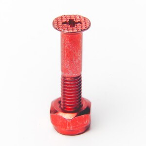 May include: A red bolt with a cross-shaped head, a cylindrical shaft, and a hexagonal nut base. The bolt is made of metal and has a textured surface. The bolt is shown against a white background.