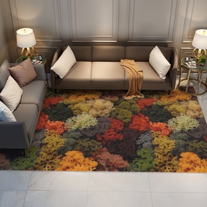 May include: A colorful area rug with a vibrant, abstract floral pattern in shades of red, orange, yellow, green, and brown. The rug is placed in a living room setting with gray sofas and accent tables.