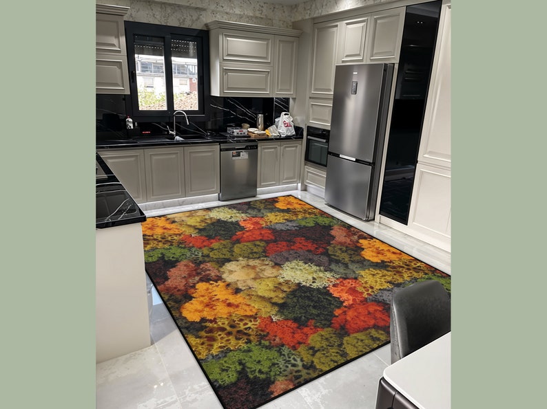 May include: A colorful area rug with a pattern of autumn foliage in shades of red, orange, yellow, and green. The rug is rectangular and placed in a kitchen setting with light gray cabinets and stainless steel appliances.
