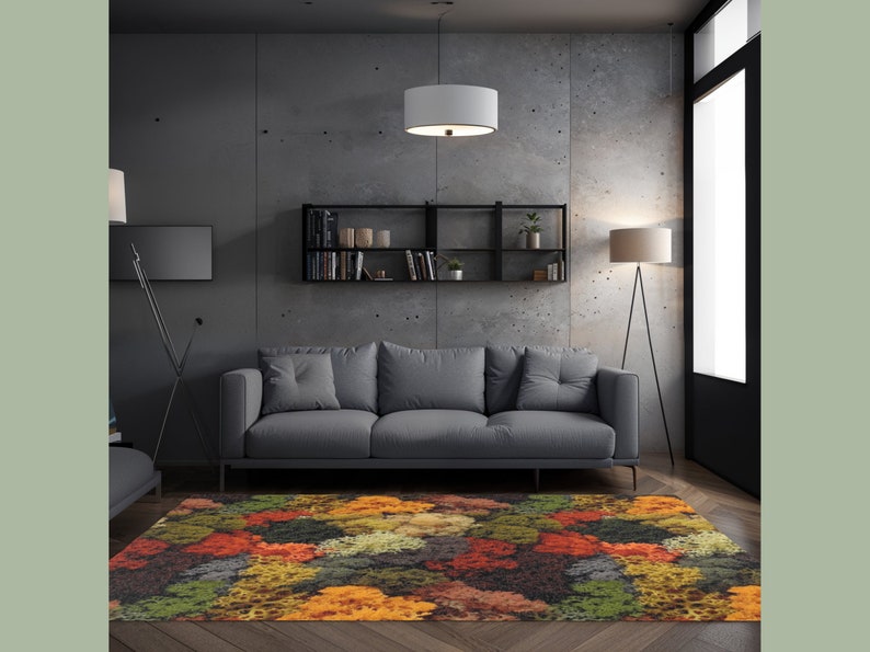 May include: A colorful area rug with a vibrant pattern of orange, red, green, and yellow hues. The rug is placed in a modern living room setting, beneath a gray sofa and in front of a concrete wall. The rug adds a pop of color to the room.