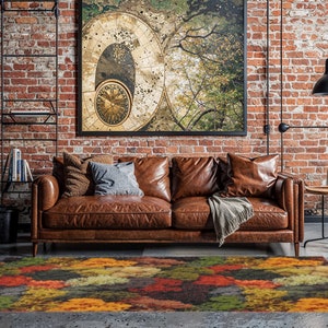 May include: A living room scene featuring a brown leather sofa, a colorful area rug with an abstract design, and a large framed artwork. The rug has a pattern of orange, yellow, green, and red hues. The room has exposed brick walls and a modern industrial aesthetic.