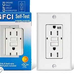 May include: White electrical outlet with a self-test GFCI safety outlet. The outlet has a white faceplate and a black test button. The text "WR" is printed on the outlet. The outlet is labeled "GFCI Self-Test Safety Outlet" and has a UL listing.