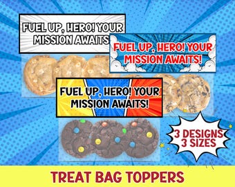 May include: Image features treat bag toppers with the text "FUEL UP, HERO! YOUR MISSION AWAITS!" in various designs. The toppers are displayed with cookies, including chocolate chip and chocolate cookies with colorful candies. The image also shows the text "3 DESIGNS 3 SIZES".