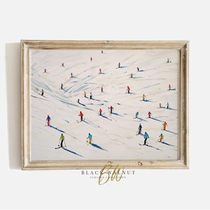 May include: A painting of a snowy mountain scene with skiers in colorful clothing. The skiers are spread out across the slope, creating a dynamic and lively composition. The painting is framed in a light wood frame.