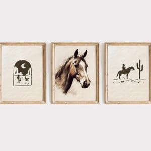 Puede incluir: Tres impresiones art&iacute;sticas enmarcadas con tem&aacute;tica del oeste. Las impresiones presentan un paisaje des&eacute;rtico con un cactus y una luna, una cabeza de caballo y un vaquero a caballo con un cactus. Los marcos son de color marr&oacute;n claro.