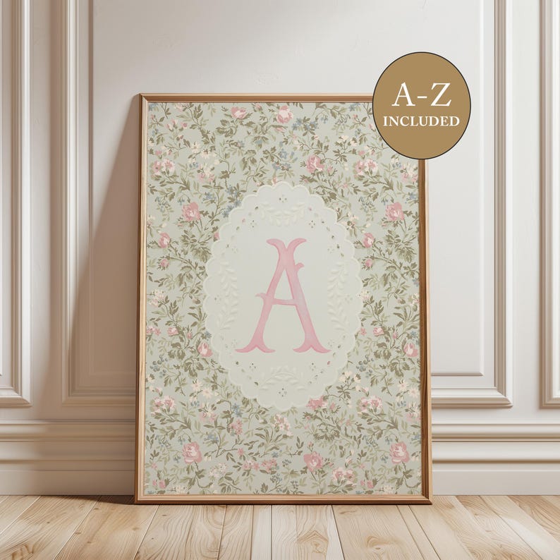 May include: A rectangular framed print featuring a light green background with a dense floral pattern of small pink roses and green leaves. A central cream-colored scalloped oval contains a large pink letter A. A brown circle displays A-Z INCLUDED.
