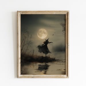 May include: A framed print of a witch dancing in a dark forest under a full moon. The witch is silhouetted against the moon and the forest. The water in the foreground reflects the moon and the witch.