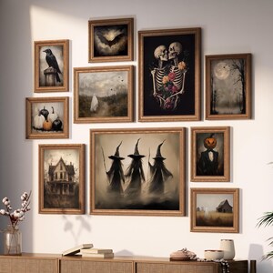 May include: A gallery wall arrangement featuring ten framed art prints with dark, atmospheric themes including skeletons with flowers, three witches, a pumpkin-headed figure, a ghost, a raven, a bat, pumpkins, and old buildings in gold frames.
