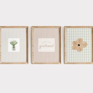 May include: Three framed art prints. The first features a watercolor of flowers in a jar on a striped background. The second has the text "long live girlhood" on a striped background. The third has a flower on a gingham background.