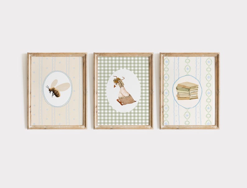 May include: Set of three framed art prints. The prints feature watercolor illustrations of a bee, a goat, and a stack of books, each within an oval frame. The frames are wooden, and the backgrounds have patterned designs in soft colors.