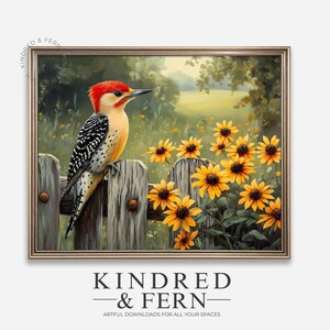 May include: A framed print depicting a painting of a red-crested woodpecker perched on a weathered wooden fence. The bird is surrounded by bright yellow sunflowers. The artwork is set against a backdrop of a sunny field and lush greenery.