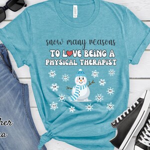 May include: A turquoise t-shirt with the text "snow many reasons TO LOVE BEING A PHYSICAL THERAPIST" and a snowman graphic. The shirt is paired with blue jeans, black sunglasses, and black sneakers.