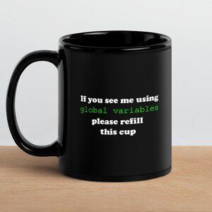 May include: Black coffee mug with white text that reads "If you see me using global variables please refill this cup". The text "global variables" is in green.
