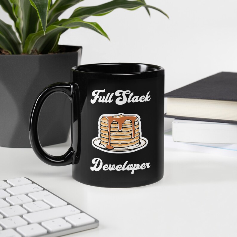 May include: Black ceramic coffee mug with a white graphic of a stack of pancakes with syrup and the text "Full Stack Developer".