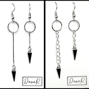 May include: Two pairs of silver earrings featuring a circle and a triangle pendant. The earrings on the left have a long, straight rod connecting the circle to the triangle. The earrings on the right have a chain connecting the circle to the triangle. The earrings are labelled "DanaR".