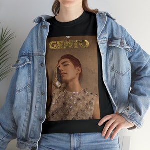 Puede incluir: Camiseta negra con un gráfico dorado de un hombre con cabello rojo que lleva una parte superior de lentejuelas doradas y un guante dorado. El texto "GENTO" está sobre la imagen.