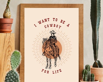 Może przedstawiać: Wydruk w ramie z beżowym tłem przedstawiający rysunek liniowy kowboja na koniu. Tekst "I WANT TO BE A COWBOY FOR LIFE" jest napisany na czerwono.