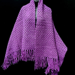May include: Purple crochet shawl with fringe. The shawl is made with a delicate open stitch pattern.