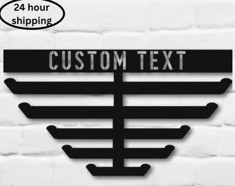 May include: Black metal wall-mounted medal display with six hooks in a triangular shape. The display has a black metal bar with the text "CUSTOM TEXT" on it.