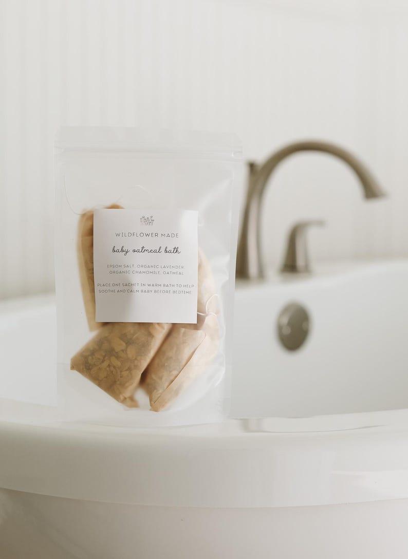 Peut inclure: Un sachet en plastique transparent contenant plusieurs sachets en tissu beige &eacute;tiquet&eacute;s Wildflower Made baby oatmeal bath, listant des ingr&eacute;dients comme le sel d'Epsom, la lavande bio, la camomille bio et l'avoine avec des instructions.