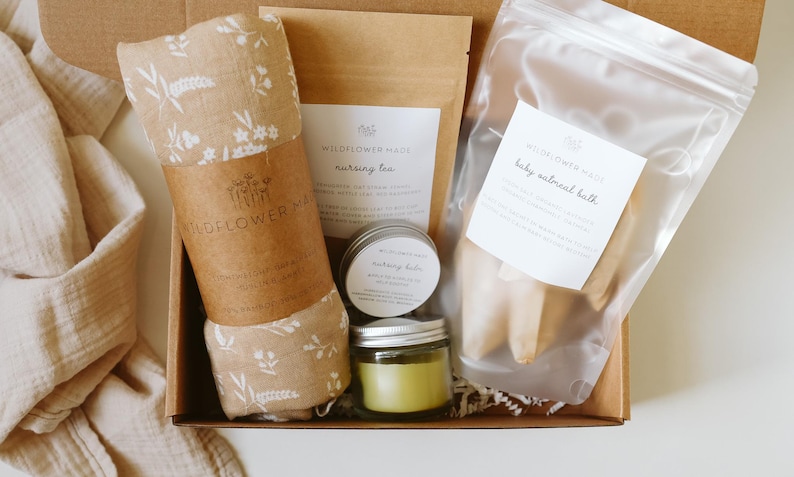 Peut inclure: Un coffret cadeau contenant un lange en mousseline beige &agrave; motif floral blanc, un sachet de tisane d'allaitement Wildflower Made, un petit pot de baume d'allaitement, un pot en verre avec une bougie verte et un sachet transparent de bain d'avoine.