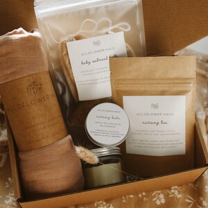Peut inclure: Un coffret cadeau contenant une couverture en mousseline rose poudr&eacute; enroul&eacute;e avec une &eacute;tiquette Wildflower Made, un sachet transparent de bain &agrave; l'avoine pour b&eacute;b&eacute;, un petit pot de baume d'allaitement et un sachet de th&eacute; d'allaitement.