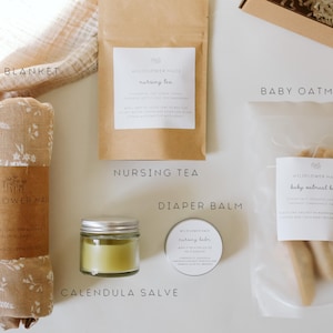 Peut inclure: Un coffret cadeau comprenant une couverture pour b&eacute;b&eacute; beige &agrave; motifs floraux, un sachet en papier brun de tisane d'allaitement, un petit pot en verre de baume au souci vert, une bo&icirc;te ronde de baume pour le change et un sachet de bain &agrave; l'avoine.