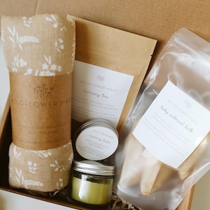 Peut inclure: Un coffret cadeau contenant une couverture en mousseline beige &agrave; motif floral blanc, un sachet de tisane d'allaitement Wildflower Made, un petit pot de baume d'allaitement, une bougie verte en pot de verre et un sachet de bain &agrave; l'avoine.