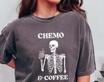 May include: A dark gray t-shirt with a white skeleton holding a cup of coffee. The text "CHEMO & COFFEE" is printed on the shirt.