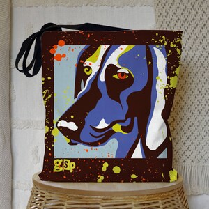 May include: A brown canvas tote bag with a colorful graphic of a dog's face. The graphic is in a pop art style with splashes of yellow, orange, and blue paint. The bag has a black strap and the text "GSP" is printed on the bottom.
