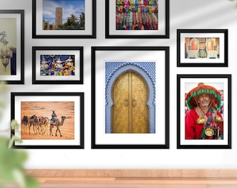 Può includere: Una collezione di stampe d'arte marocchina incorniciate che presentano una varietà di soggetti, tra cui una carovana di cammelli, una porta tradizionale, un uomo con un cappello e una natura morta. Le stampe sono disposte su una parete bianca con un pavimento in legno sottostante. Il testo "Moroccan Art" e "Oriental Collection 55 Print" è visibile nell'immagine.