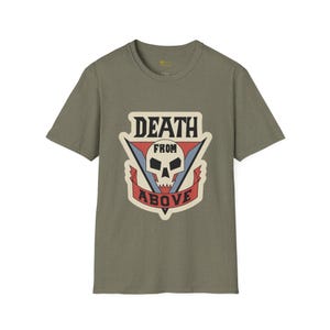 May include: An olive green short-sleeve t-shirt featuring a graphic print on the chest. The design includes a white skull centered within a red and blue triangular emblem, with the black text DEATH FROM ABOVE displayed in a bold font.