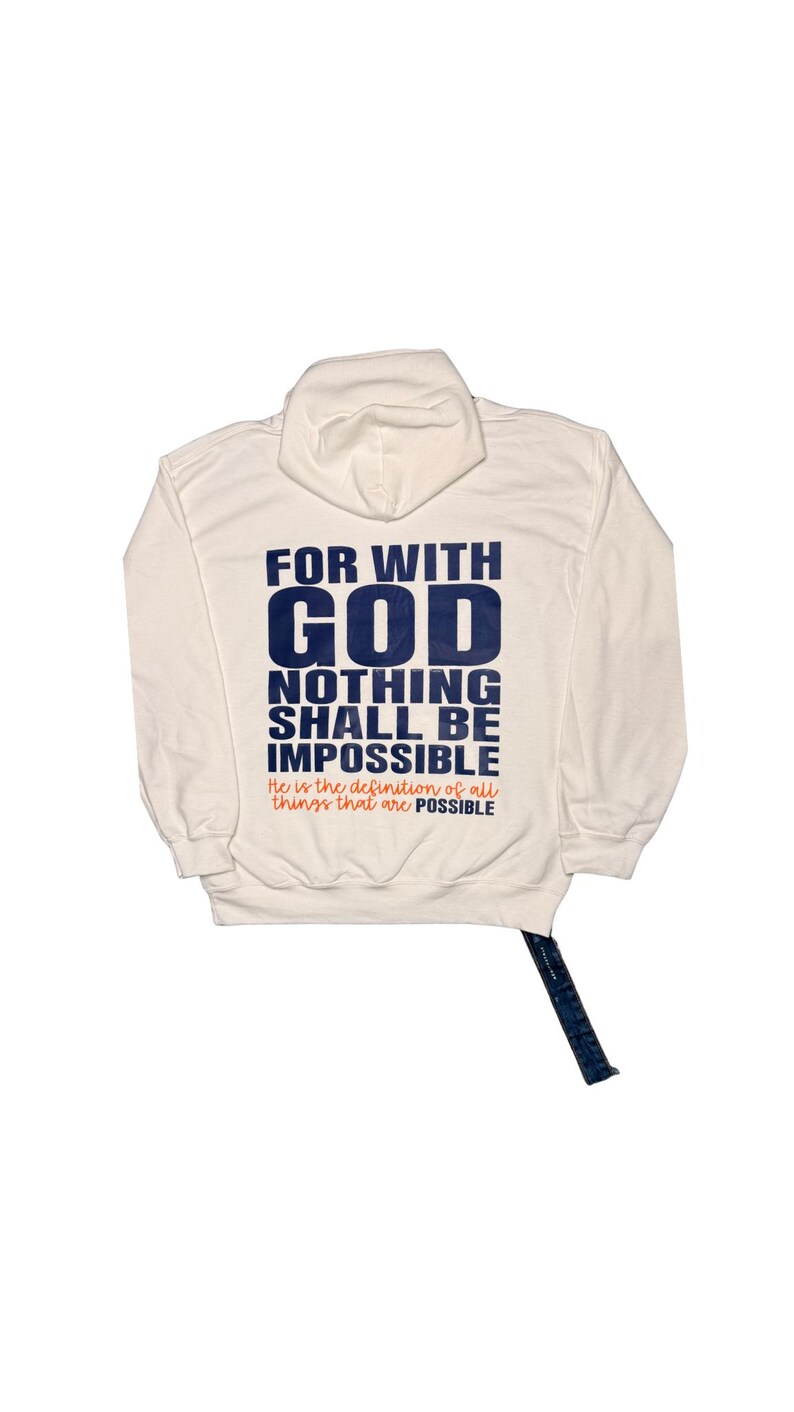 Puede incluir: Sudadera con capucha color crema con el texto "FOR WITH GOD NOTHING SHALL BE IMPOSSIBLE" en azul marino. La frase "He is the definition of all things that are POSSIBLE" est&aacute; impresa debajo en naranja. La sudadera tiene un cord&oacute;n y un bolsillo de canguro.
