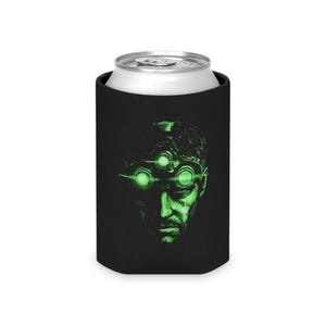 Puede incluir: Enfriador de latas negro con una imagen teñida de verde del rostro de un hombre, con tres círculos verdes brillantes sobre sus ojos. El enfriador está diseñado para mantener las bebidas frías.