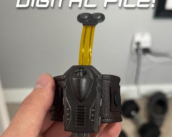 May include: A black wristband with a yellow and black extension. The wristband has a textured leather strap and a black plastic casing with a small, round, black button on the top. The extension has two small, round, black buttons on the top.