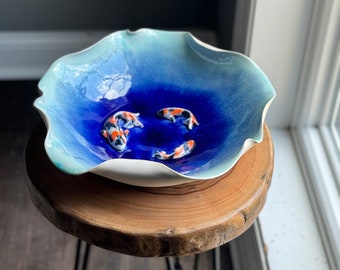 handmade wheel thrown ceramic porcelain pottery serving bowl. Art centerpiece with Koi fish in water or glass like blue pool of glaze