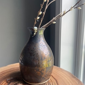 A fine art bronze/gold vase with a sculpted accent. It is handmade and wheel thrown piece of functional art.