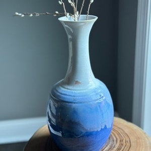 Handmade, wheel-thrown pottery, tall vase made of porcelain. It is a big statement piece in a flowing glaze of white into blue.