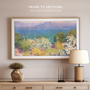 May include: A framed painting of a landscape with a body of water in the distance, green trees, and white flowers in the foreground. The painting is hanging on a wall above a wooden dresser.